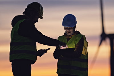 Corporate sustainability image of two workers in front of a windmill