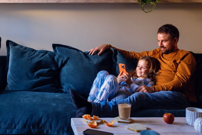 Wealth succession planning image of a father and daughter relaxing on a blue couch