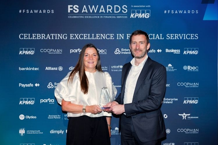 Two people holding the FS Awards wealth manager of the year award in front of a blue backdrop
