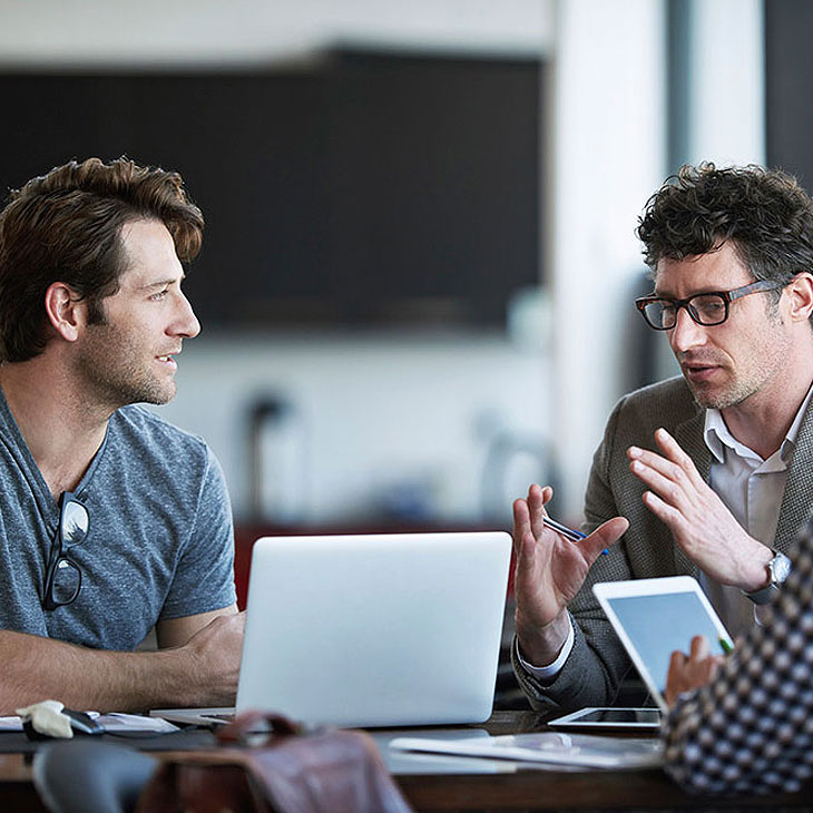 Marketplace image of two people talking in front of laptop