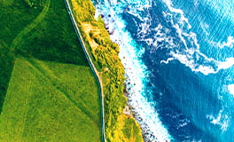 The sea meeting a green coast from overhead