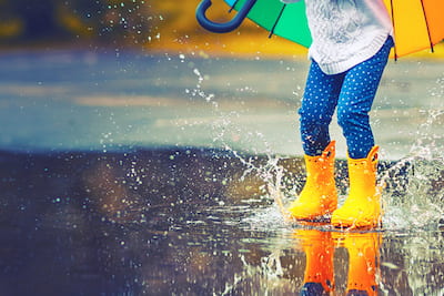 April newsletter image of a kid dancing in the rain