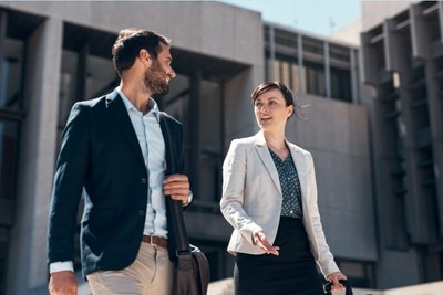Business man and women, walking and talking outside office building