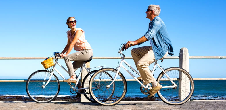 Wealth management planning image of a couple cycling by the sea