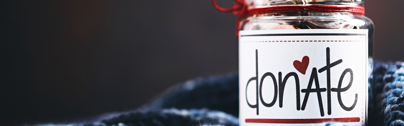 Inspiring children to donate money to charitable causes. Image shows a glass jar filled with coins with word donate on the front