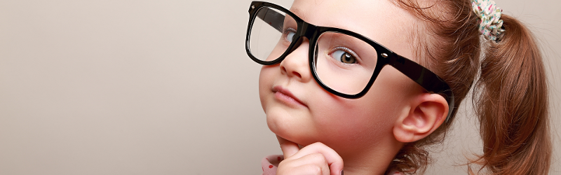 10 money lessons to learn from a young age. Image of young girl wearing adult-sized glasses.