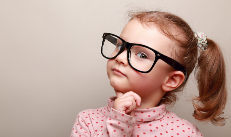 10 money lessons to learn from a young age. Image of young girl wearing adult-sized glasses.