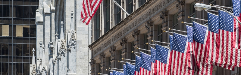 Image of multiple USA flag hung from a building