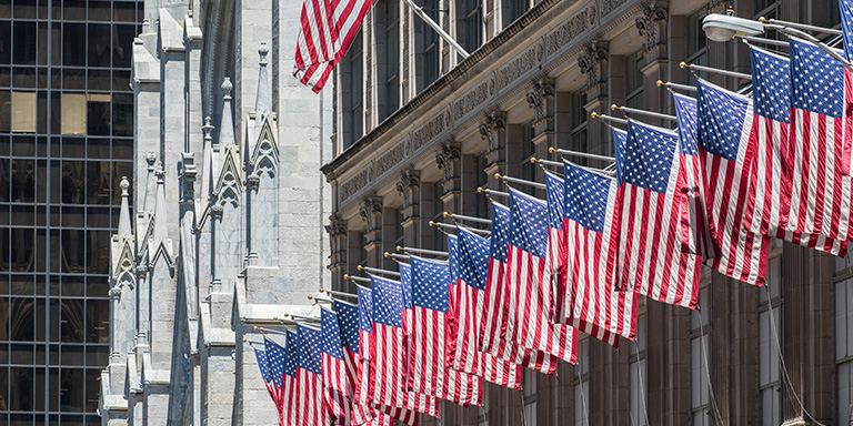 Image of multiple USA flag hung from a building