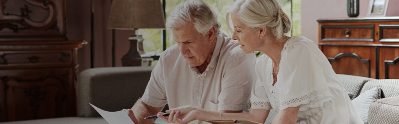 Image of couple on a couch reading a piece of paper