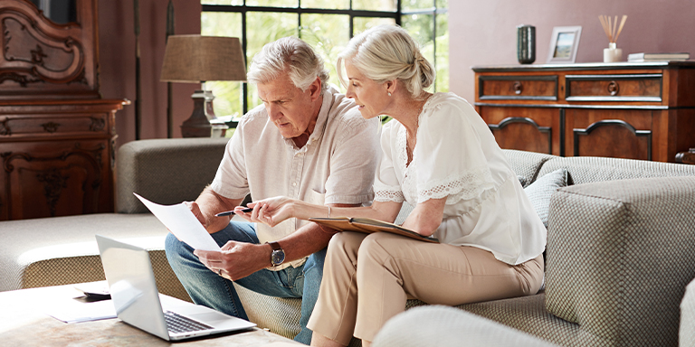 Image of couple on a couch reading a piece of paper