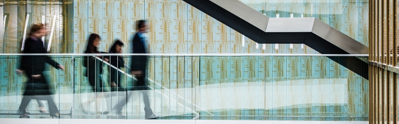 Blurred image of corporate professionals walking across a skybridge in an office