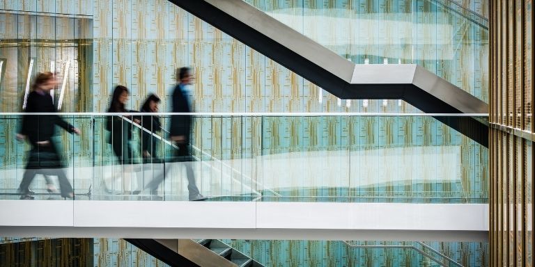 Blurred image of corporate professionals walking across a skybridge in an office