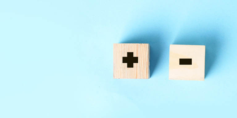 Great companies can make terrible investments. Image of two wooden blocks, one with plus sign, one with minus sign, on a blue background