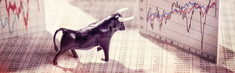 Marketwatch image of a toy bull sitting on some print outs of graphs