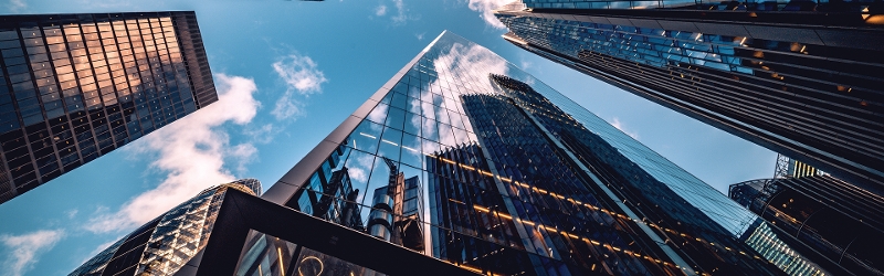 Looking up to a blue sky surrounded by skyscrapers