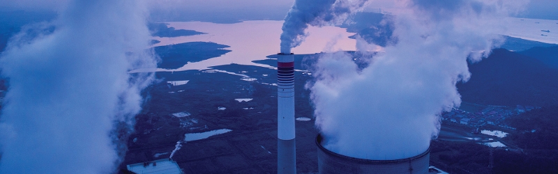What are carbon credits? Image shows billowing smoke coming out of chimneys with landscape in background