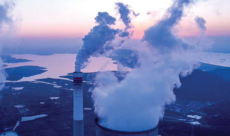 What are carbon credits? Image shows billowing smoke coming out of chimneys with landscape in background