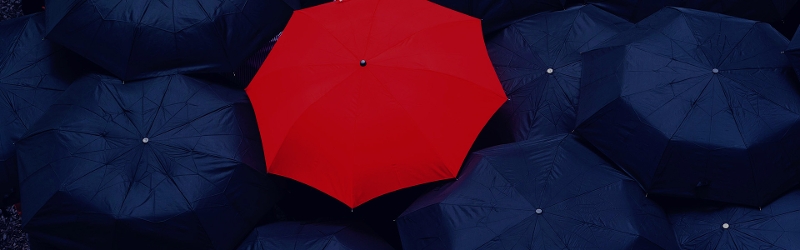 Open red umbrella amongst open dark navy umbrellas