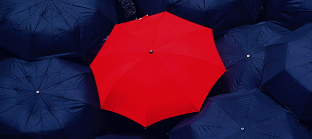 Open red umbrella amongst open dark navy umbrellas