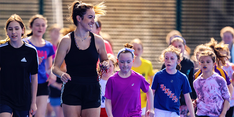 Interview with Hannah McLoughlin. Hannah coaching kids on the hockey pitch.