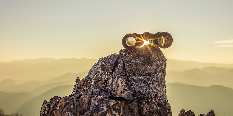 Equities image of a set of binoculars sitting on a rock